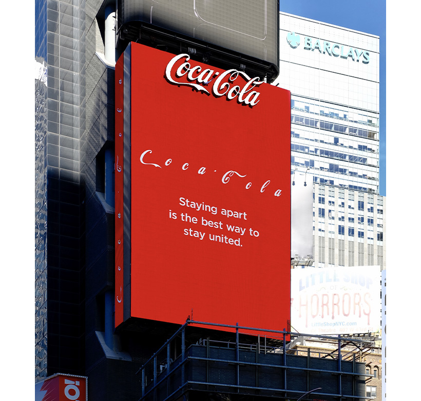 A huge Coca-Cola billboard in Times Square that reads "Staying apart is the best way to stay united.